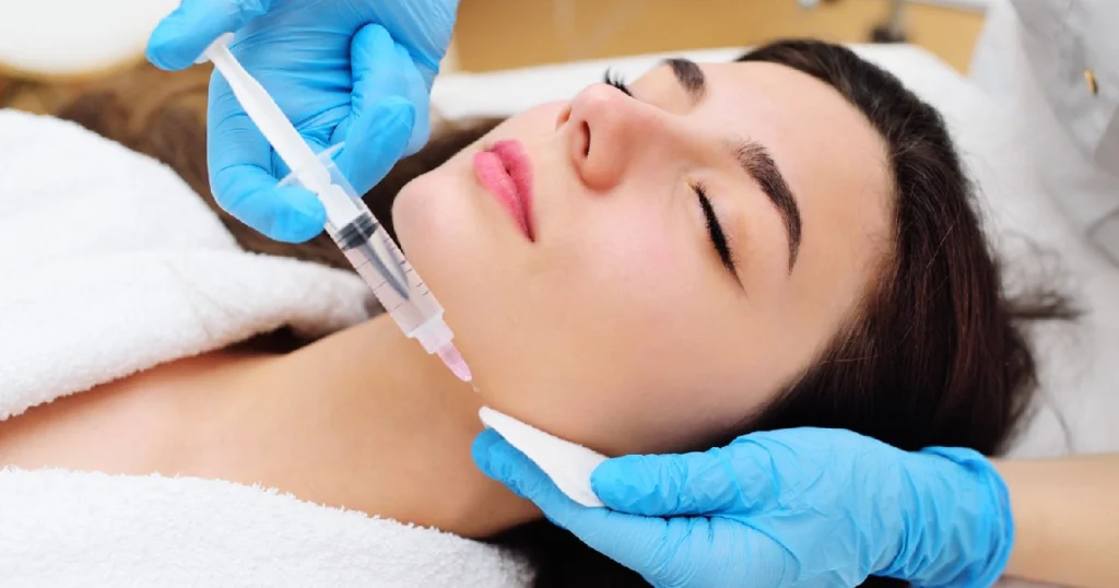 Current image: Woman receiving Kybella® treatment in New York, NY under the chin to reduce fullness and achieve a slimmer profile.